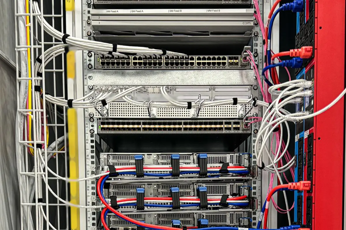 Top of a rack at a customer site: a patch panel labelled for the multimode and singlemode feeds, a copper switch with its cables bundled, a second switch, and the first servers below